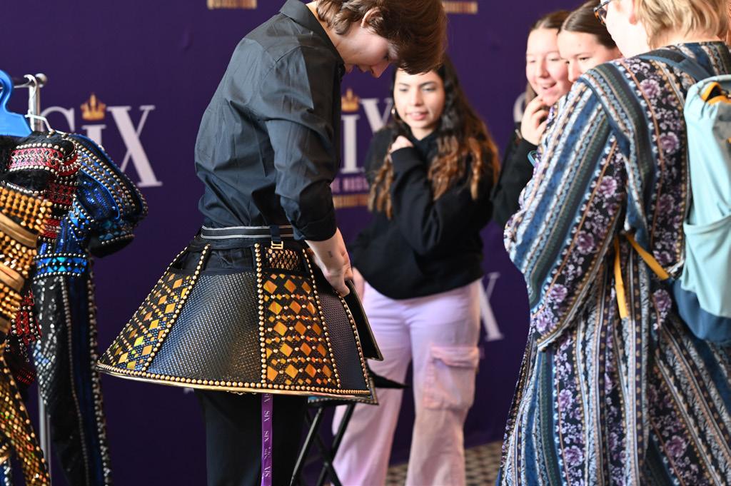 Students look closely at studded queen costumes from SIX